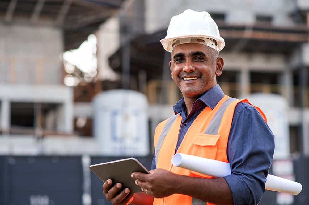 constructor worker with hard hat holding a tablet and smiling