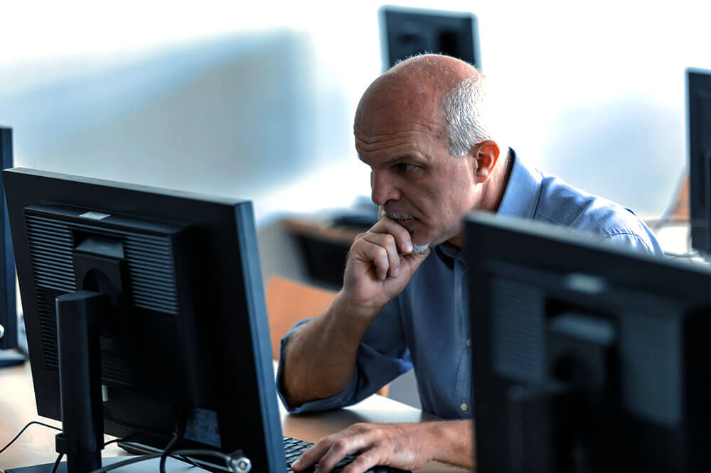 man sitting at desktop computer looking at screen