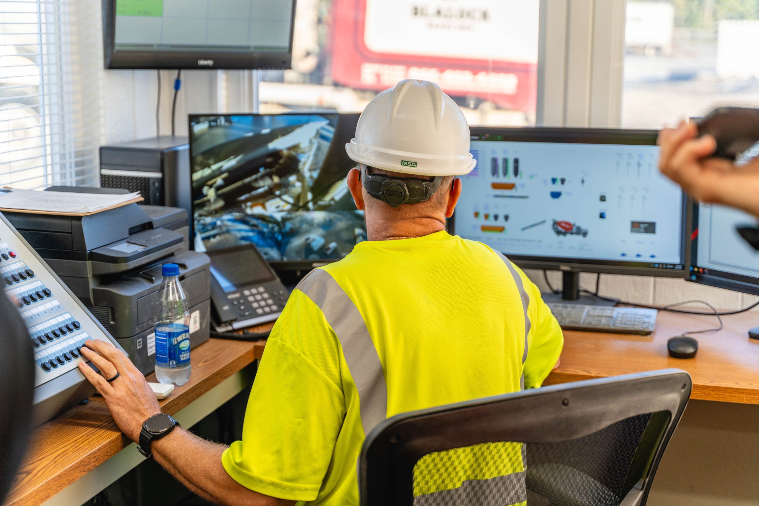 man in dispatch office pointing at computer screen